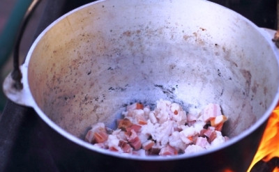 1. Этап. Кулеш на костре: На дно котелка выкладываем нарезанное кубиками 200 г. сала и копченую грудинку. Жарим до тех пор, пока не вытопится жир и кусочки не подрумянятся.