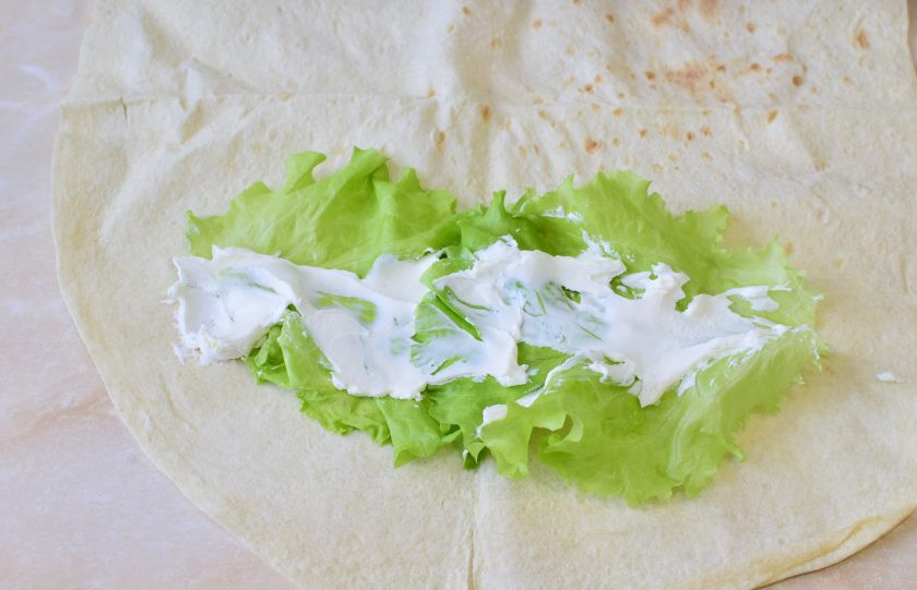 1. Этап. Сэндвич ролл с креветкой: На столе разложите лист лаваша. Выложите листья салата и смажьте их творожным сыром.