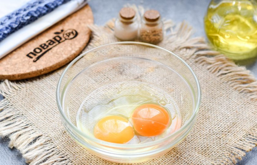 1. Этап. Рецепт завтрака из яиц: Возьмите небольшую глубокую миску, вбейте два куриных яйца, добавьте щепотку соли.