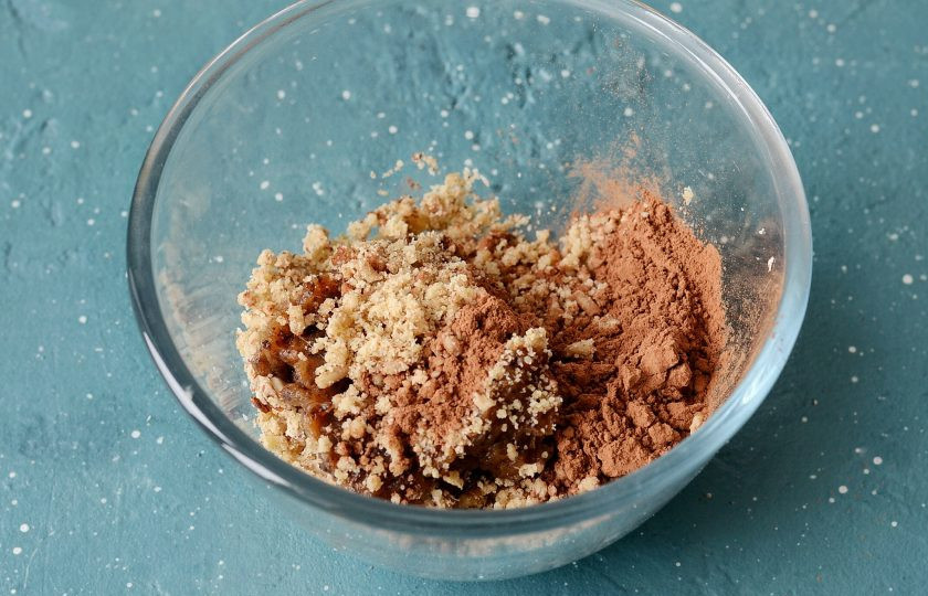 1. Этап. Конфеты из фиников и орехов без сахара: Добавьте в миску с орехами финики, какао и кокосовую стружку. Перемешайте до однородной массы.