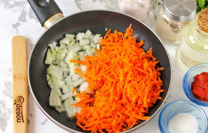 1. Этап. Борщ по ГОСТу: В это время морковь натрите на терке с крупными ячейками, репчатый лук нарежьте мелким кубиком. Отпассеруйте овощи на сковороде в 1 ст.л. растительного масла до мягкости.