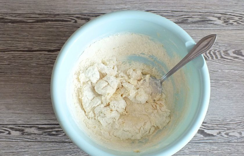 1. Этап. Ватрушки с бананом: Начните замес ложкой, постепенно подсыпая остаток муки. Когда станет сложно перемешивать, месите руками.