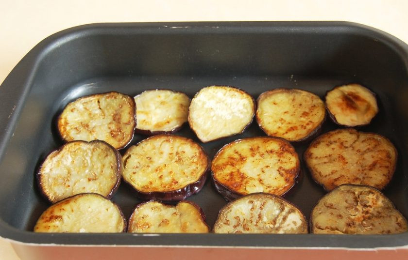 1. Этап. Мясная запеканка с гречкой: Баклажан обжарьте на сковороде с маслом по три минуты на каждую сторону. Выложите первым слоем в форму для запекания.