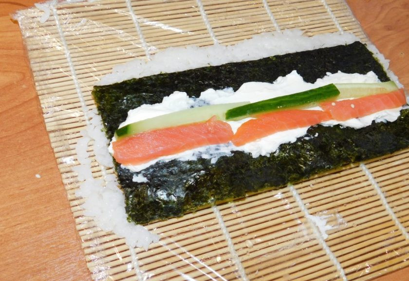 1. Этап. Роллы Бонито: Уложите в ряд начинку: творожный сыр, огурцы и рыбу.
