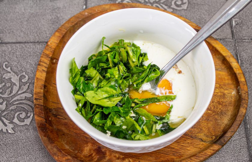 1. Этап. Трёхслойный торт-омлет: Для второго омлете в подходящую мисочку вбейте 2 куриных яйца, 1 столовую ложку сливок, соль и перец по вкусу. Свежий шпинат нарежьте мелко и добавьте в омлетную массу.