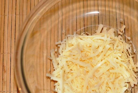 1. Этап. Салат Мимоза с сыром: Возьмите салатницу подходящего размера. Потрите сыр и выложите половину его первым слоем.