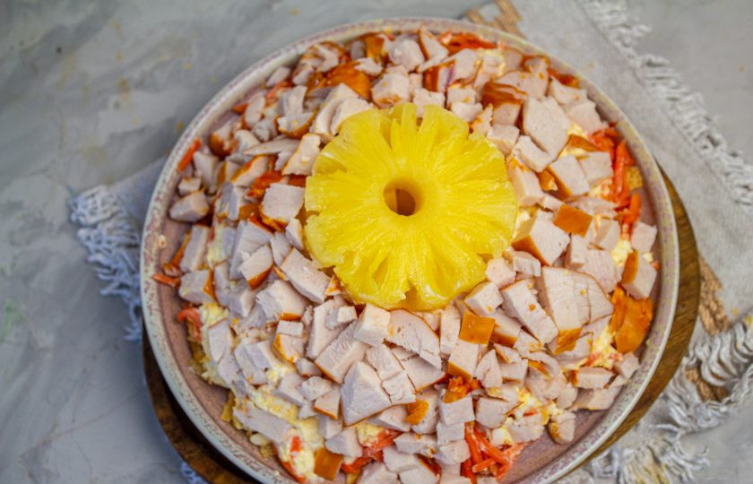 1. Этап. Салат Ананасовое кольцо: Копченую куриную грудку нарежьте небольшим кубиком и выложите следующим слоем.