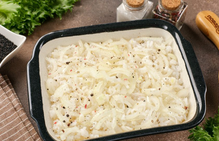 1. Этап. Пирог с сайрой и рисом: Жаропрочную форму смажьте маслом. Дно и бока обсыпьте мукой или манкой. Налейте примерно 2/3 теста и сверху выложите отваренный рис. На рис выложите нарезанный тонкими полукольцами лук. Посолите и поперчите начинку по вкусу.