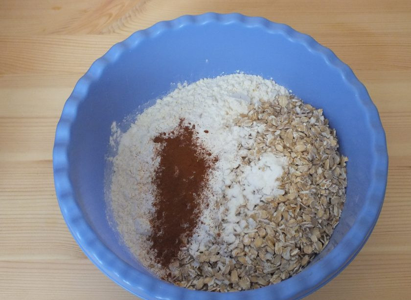 1. Этап. Печенье из яблок и бананов: В чаше смешайте сыпучие ингредиенты: 2 стакана муки, сахар, овсяные хлопья, корицу и разрыхлитель для теста. Остальные 0,5 стакана добавьте по необходимости во время замеса.