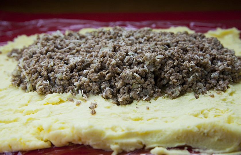 1. Этап. Картофельный рулет с мясом: Выкладываем теперь ровненьким слоем пюре на пищевую пленку. Сверху кладем фарш, делаем отступ от краев пюре в пару сантиметров.