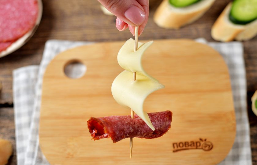 1. Этап. Канапе Кораблик: Возьмите любую шпажку, нанизайте на нее сначала маленький парус, потом большой и в конце ломтик колбасы, скрученный в трубочку.