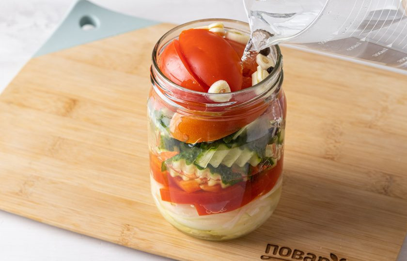 1. Этап. Салат на зиму с огурцами и помидорами: Влейте в банку кипяток. Прикройте крышкой.