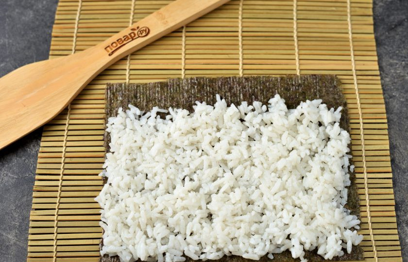 1. Этап. Роллы с икрой мойвы: Положите на циновку лист нори, на нори выложите тонким слоем рис, край водорослей с противоположной стороны оставьте свободным.