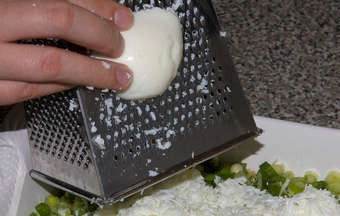 1. Этап. Салат из ставриды: На наш зеленый слой салата натираем белки от сваренных вкрутую яиц( желтки понадобятся нам для верхнего слоя).Разравниваем слой белков по поверхности салата, солим, перчим и смазываем майонезом.