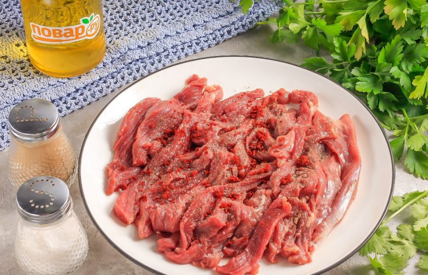 1. Этап. Соломка из говядины с репчатым луком: Мякоть говядины нарежьте на пластины, а их — соломкой, лентами. Посолите и поперчите мясо.