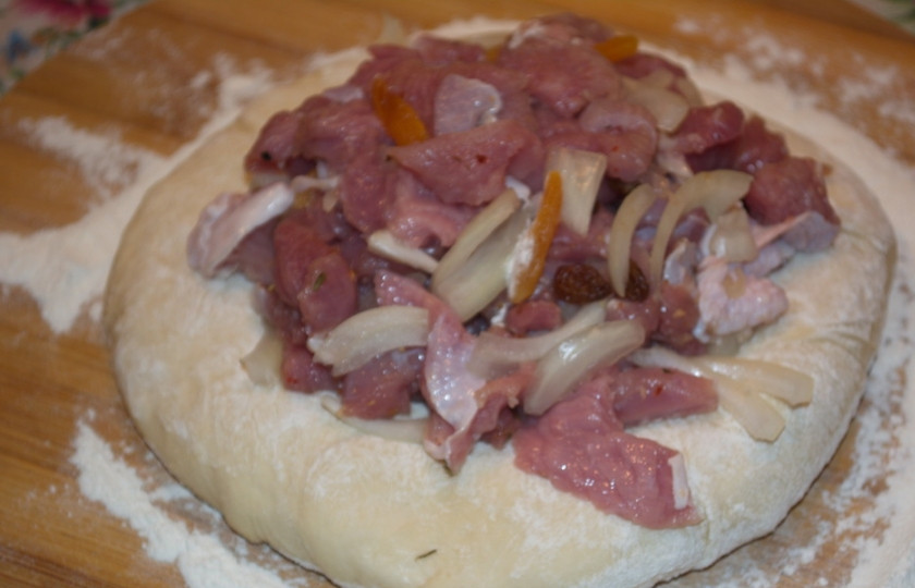 1. Этап. Осетинский пирог Царский: В середину получившейся лепешки выложите порцию мясной начинки. Количество теста по объему должно быть равным количеству мяса. Соберите края теста, заключив начинку внутри. Не порвите тесто.