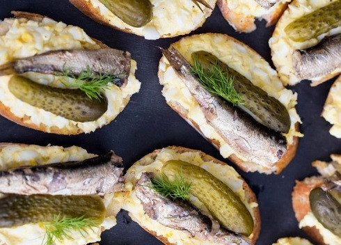 1. Этап. Бутерброды со шпротами и соленым огурцом: И теперь формируем наши бутерброды. На ломтики батона выкладываем яичную смесь, выкладываем рыбку и ломтик огурца. И украшаем веточкой зелени.