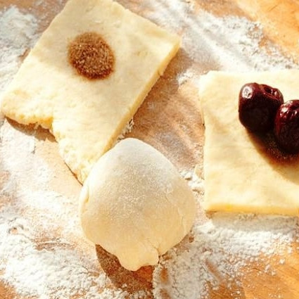 1. Этап. Картофельные гомбовцы: Получившееся тесто разрезаем на две части. Одну часть раскатываем в тонкий (3-4 мм) пласт и разрезаем на небольшие квадратики. В центр каждого квадратика кладем немного корицы с сахаром и пару вишен без косточек. Сворачиваем гомбовец в шарик.