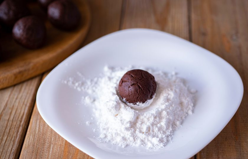 1. Этап. Шоколадное треснутое печенье: Затем от общей массы охлажденного теста отщипывайте по небольшой части весом примерно в 30 грамм. Скатайте шарики из каждой такой части и обваляйте каждый в сахарной пудре.