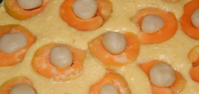 1. Этап. Абрикосовый пирог с марципаном: Форму для выпечки застилаем пекарской бумагой, вливаем тесто и кладем на него абрикосы (начинкой к верху).