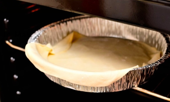 1. Этап. Вкусный пирог: Один тонко раскатанный пласт теста поместите на дно и борта формы. Духовку разогрейте до 180 градусов и запекайте корж 9-10 минут.