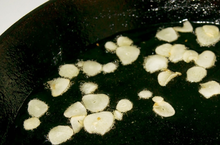 1. Этап. Рыба тушеная с картофелем: Чеснок нарежьте тонкими дольками и обжарьте на маленьком огне в оливковом масле.