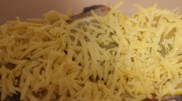 1. Этап. Рыба дори в духовке: Полутвердый сыр натрите на крупной терке. Для этого идеально подойдет Гауда. Выложите сыр на кусочки рыбы и кружочки лимона и равномерно распределите его по всей поверхности.