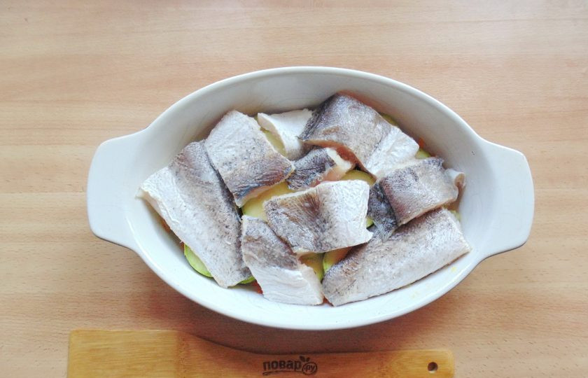 1. Этап. Хек с кабачками в духовке: Рыбу нарежьте на кусочки, выложите поверх кабачков. Посолите и поперчите.