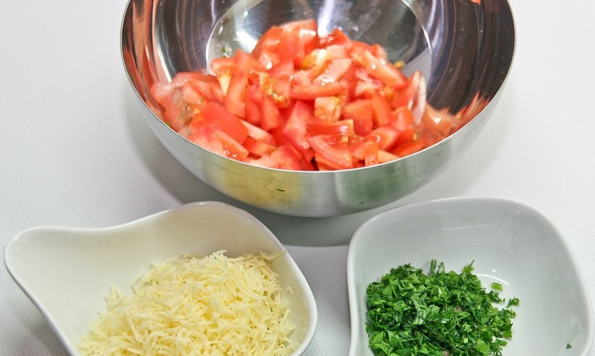 1. Этап. Слоеная картошка со свининой: 8. Подготовьте овощи для подачи блюда. Помойте помидоры и зелень. Помидоры нарежьте мелкими кусочками. Зелень порубите. Натрите сыр на мелкой терке.