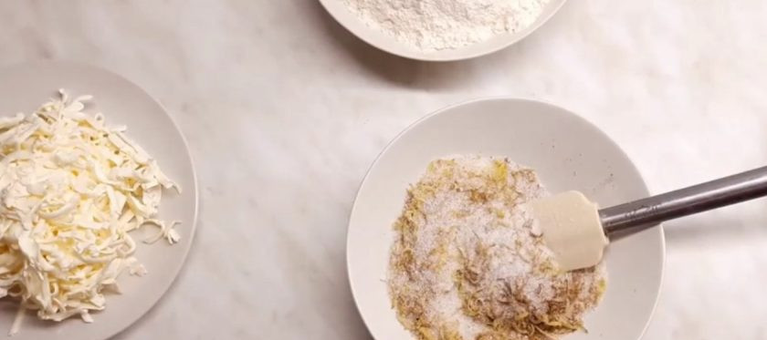 1. Этап. Дрезденский штоллен: 4. Добавьте в сахар мускатный орех, ванильный сахар, цедру лимона. Перемешайте. Немного посолите. Молоко с яйцами вылейте в миску, добавьте натертый маргарин и сахар со специями, перемешайте и добавьте дрожжи. Аккуратно перемешайте массу.