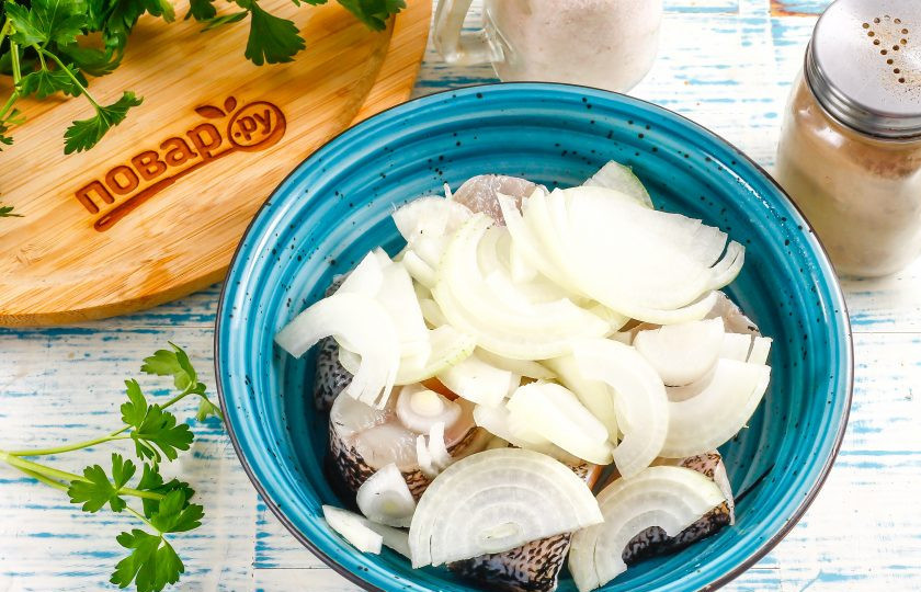 1. Этап. Щука маринованная в уксусе с луком: Репчатый лук разрежьте пополам и нарежьте полукольцами. Добавьте луковую нарезку к рыбной.
