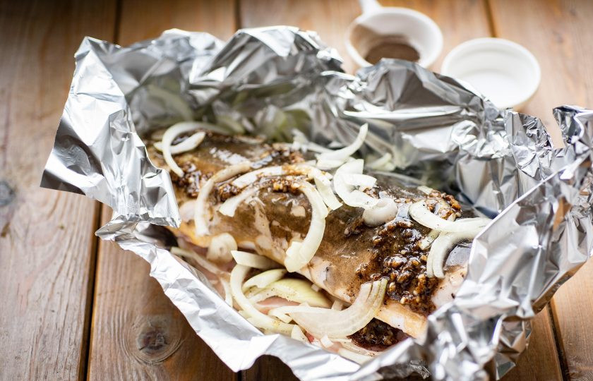 1. Этап. Карп в аэрогриле: Выложите почищенную рыбку на фольгу, сверху обильно полейте приготовленным маринадом, поверх разложите тонкие полукольца лука. Края фольги поднимите и хорошо закрепите пальцами, закрывая карпа.