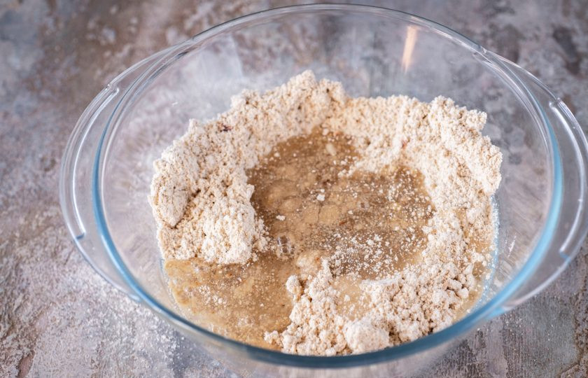 1. Этап. Домашняя халва: Из чаши блендера выложите смесь из измельченных семечек и муки в просторную миску, залейте растительное масло и сироп. Перемешайте.