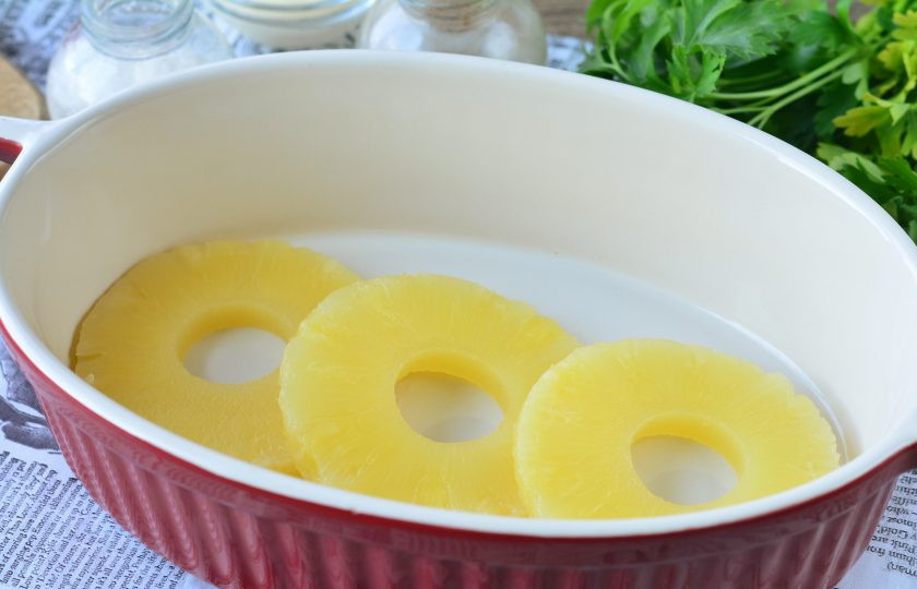 1. Этап. Ананасы под сыром в духовке: Форму для запекания смажьте маслом, выложите кольца ананасов.