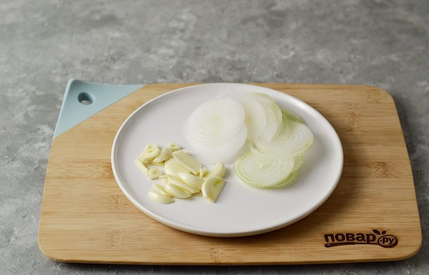 1. Этап. Огурцы в банку на зиму: Лук нарежьте тонкими колечками. Чеснок очистите и нарежьте пластинами.