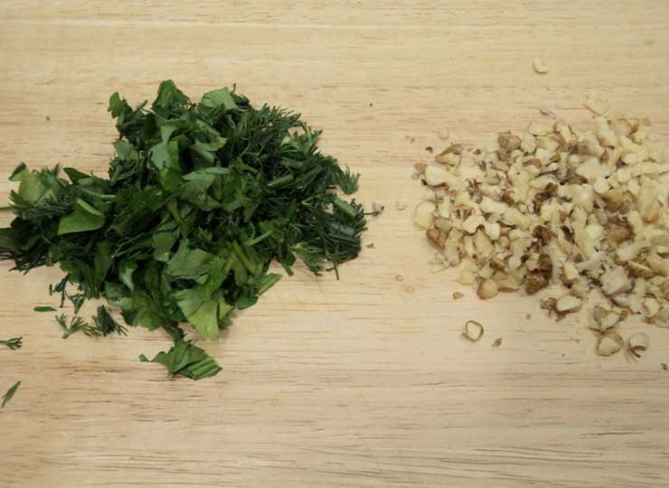 1. Этап. Рулетики из яичных блинчиков: Измельчите зелень, а грецкие орехи растолките.