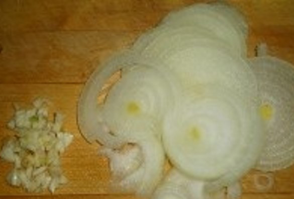 1. Этап. Соус с курицей для спагетти: Лук порежьте полукольцами, чеснок измельчите.