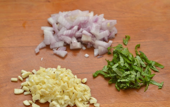 1. Этап. Филе цыпленка: 4. Параллельно очистите и измельчите лук с чесноком, а также вымытые и обсушенные листочки базилика.