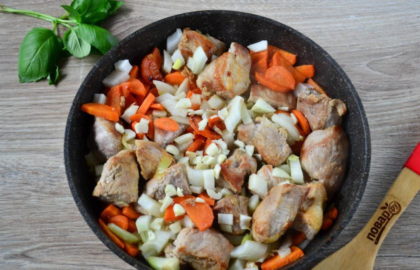 1. Этап. Гуляш из свинины с морковью и луком: Отправьте лук с морковью в сковороду к мясу, туда же положите мелко нарезанный чеснок, перемешайте и обжарьте на среднем огне 5-7 минут.