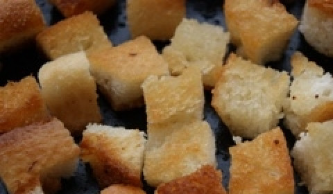 1. Этап. Салат Цезарь с колбасой: Батон освободить от корки и нарезать кубиками со стороной примерно 1 сантиметр. Выложить на противень, сбрызнуть маслом и поджарить до золотистого цвета. Можно это сделать и на сковороде, главное, чтобы крутоны не получились слишком жирными.