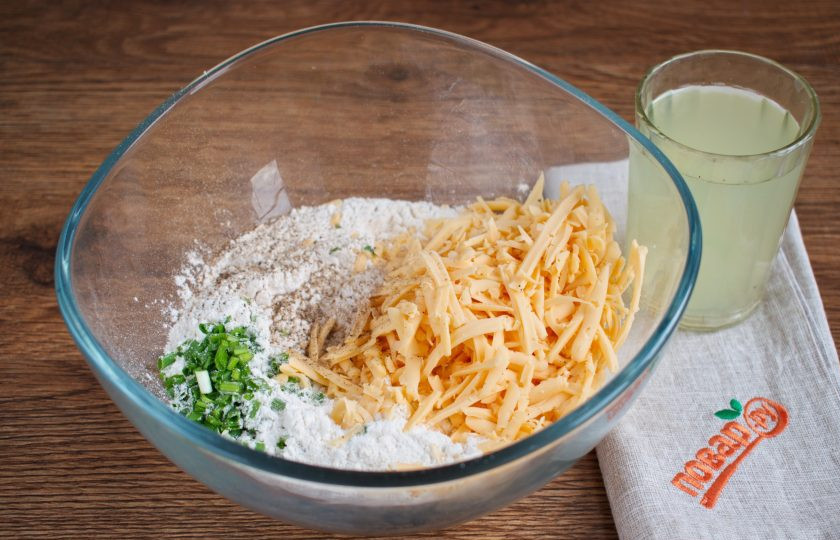 1. Этап. Острое печенье: Муку просейте в миску. Зеленый лук измельчите. Холодное сливочное масло натрите на крупной терке или мелко порубите ножом. Соедините все ингредиенты, кроме сыворотки, в миске, перемешайте. Влейте сыворотку, замесите мягкое тесто. Заверните его в пищевую пленку, поместите в холодильник на 10 минут. За это время разогрейте духовку до 200 градусов.