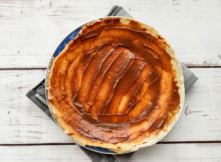 1. Этап. Блинный торт со сгущенкой и бананами: Возьмите блин, выложите его на тарелку и смажьте блинчик сгущенкой.