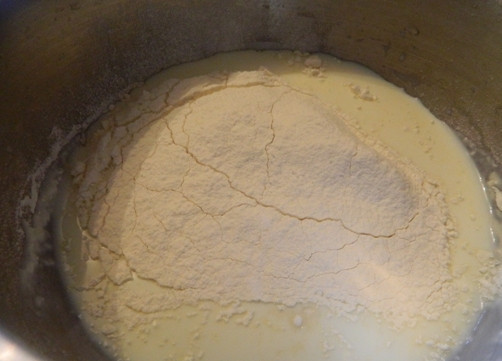 1. Этап. Быстрый торт на сковороде с заварным кремом: Первым делом приготовим заварной крем. В кастрюлю добавляем молоко, 2 ст. ложки муки, сахар и ванилин. Взбиваем миксером 20 секунд.