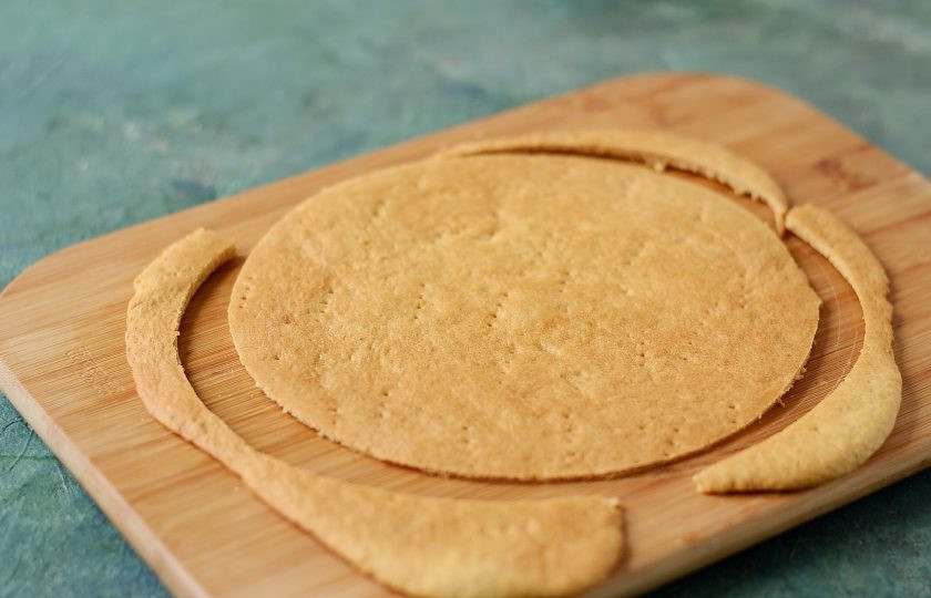 1. Этап. Постный медовик: Обрежьте коржи до нужного размера, пока они еще горячие. Обрезки отложите в сторону.