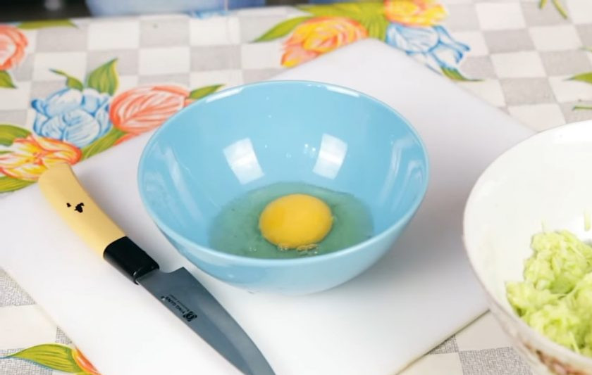 1. Этап. Простые оладьи из кабачков: 2. Через некоторое время отожмите кабачок руками. Мелко нарежьте чеснок и добавьте к кабачкам. Затем в отдельной миске слегка взбейте вилкой яйцо и добавьте к кабачкам.