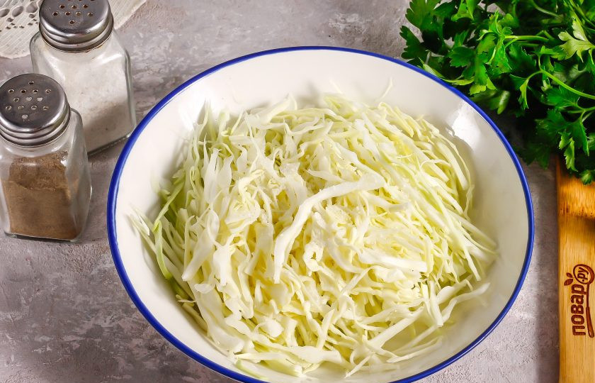 1. Этап. Салат из капусты с кукурузой и яйцом: Снимите верхний лист с части капусты, мелко нарежьте и выложите нарезку в глубокую емкость: миску или салатник. Всыпьте соль и молотый черный перец. С усилием протрите всю нарезку между собой, чтобы она выпустила сок.