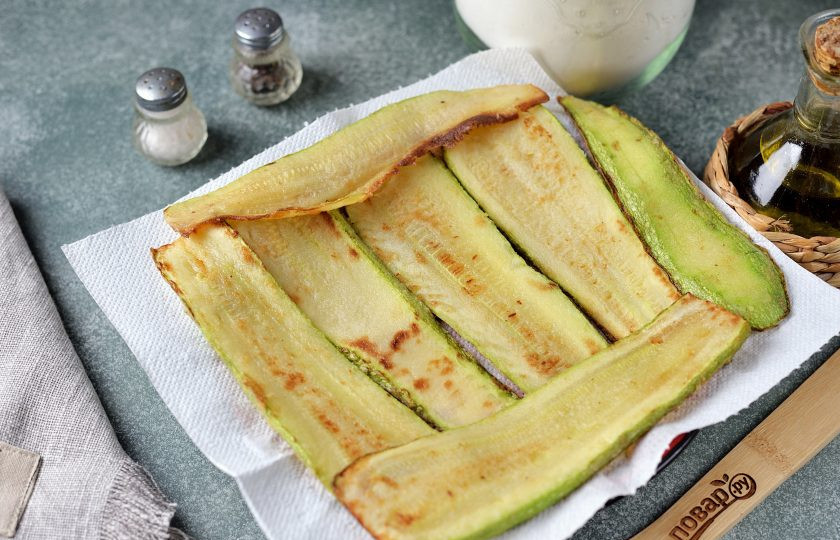 1. Этап. Рулетики из кабачков с огуречно-сырной начинкой: Выложите обжаренные ломтики кабачка на бумажное полотенце, чтобы убрать излишки масла.