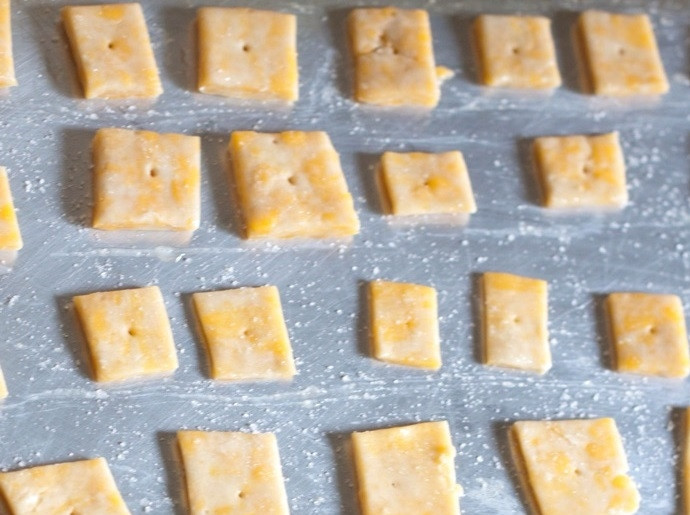 1. Этап. Домашние сырные крекеры: 3. Выложите квадратики на смазанный растительным маслом противень, проткните зубочисткой каждый и смажьте слегка взбитым белком.