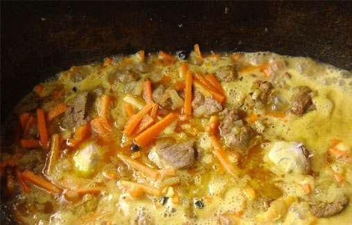 1. Этап. Плов из баранины на костре: 3. Когда морковь станет мягкой, - добавим очищенные, но целые головки чеснока, специи по вкусу и заливаем водой, чтобы чуть покрывала овощи.