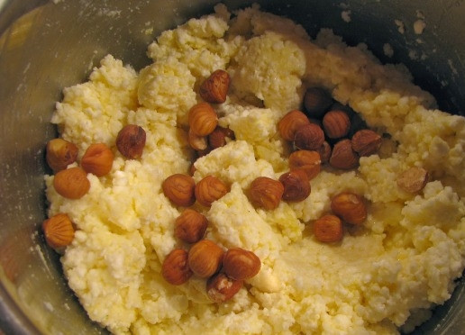 1. Этап. Рецепт домашнего сыра из молока и творога: Сюда же добавляем фундук. Ставим кастрюлю с будущим сыром в большую кастрюлю с водой (делаем водяную баню). Затем отправляем кастрюли на маленький огонь и варим сыр, постоянно помешивая, минут 15.